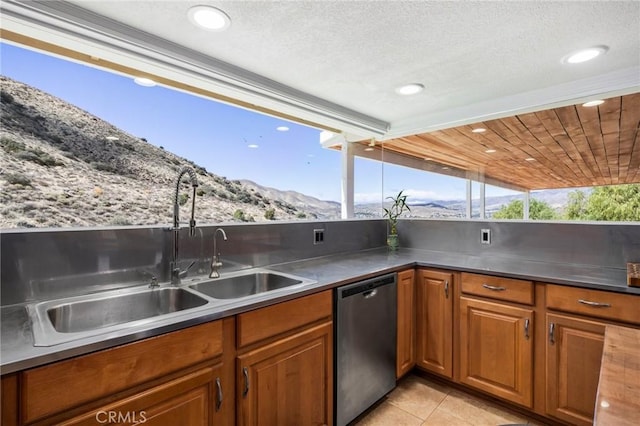 kitchen with light tile patterned floors, a mountain view, a sink, dishwasher, and brown cabinetry