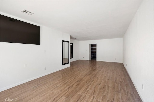 unfurnished room featuring light wood-type flooring, visible vents, and baseboards