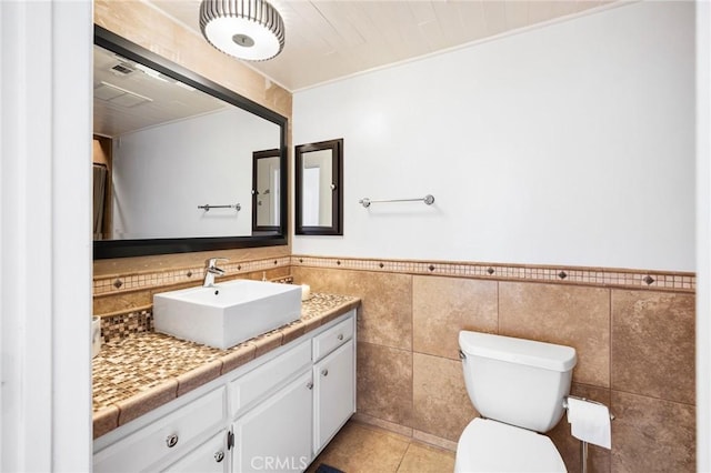 bathroom featuring tile walls, toilet, wainscoting, vanity, and tile patterned floors