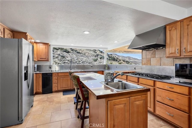 kitchen with a center island with sink, decorative backsplash, wall chimney exhaust hood, stainless steel appliances, and a sink