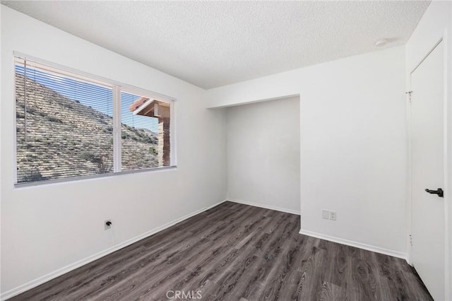 unfurnished bedroom featuring a textured ceiling, baseboards, and dark wood-type flooring