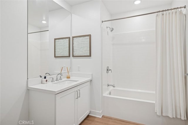 bathroom with recessed lighting, shower / bathtub combination with curtain, wood finished floors, and vanity