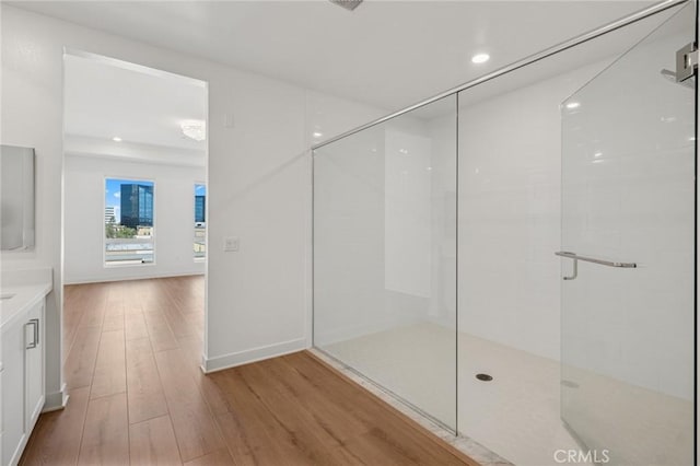 full bathroom with a shower with shower door, recessed lighting, wood finished floors, vanity, and baseboards