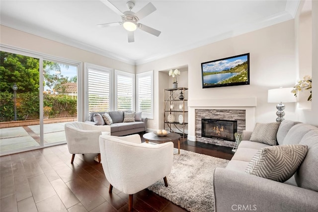 living area featuring crown molding, a ceiling fan, a fireplace, and wood finished floors