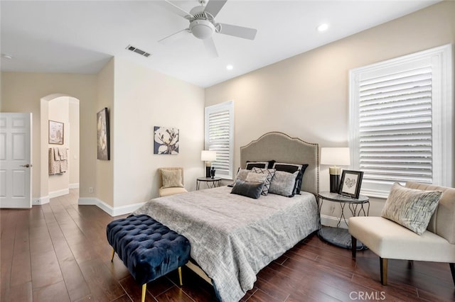 bedroom featuring baseboards, visible vents, arched walkways, and dark wood-style flooring