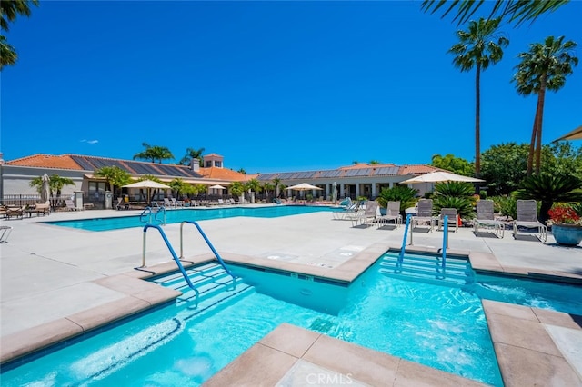 community pool with a patio area and fence