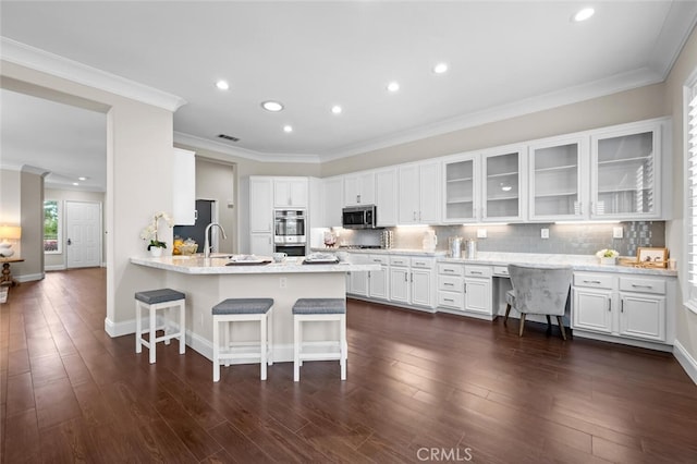 kitchen with white cabinets, appliances with stainless steel finishes, a peninsula, a kitchen bar, and backsplash