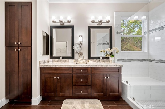 full bathroom featuring wood finish floors, double vanity, ornamental molding, a sink, and a tile shower