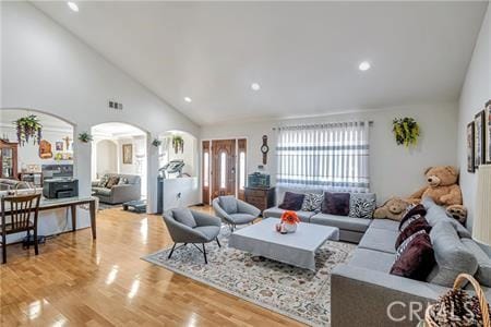 living area with high vaulted ceiling, arched walkways, recessed lighting, and wood finished floors