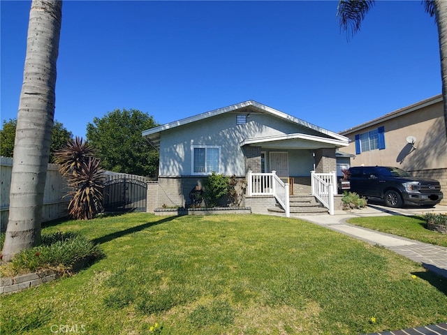 bungalow-style home with fence, brick siding, a front lawn, and a gate