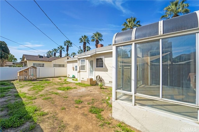 rear view of house with crawl space and fence