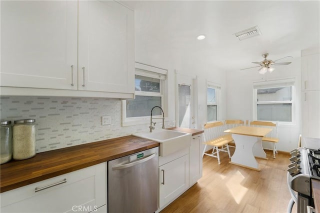 kitchen featuring butcher block counters, a sink, stainless steel dishwasher, light wood finished floors, and tasteful backsplash