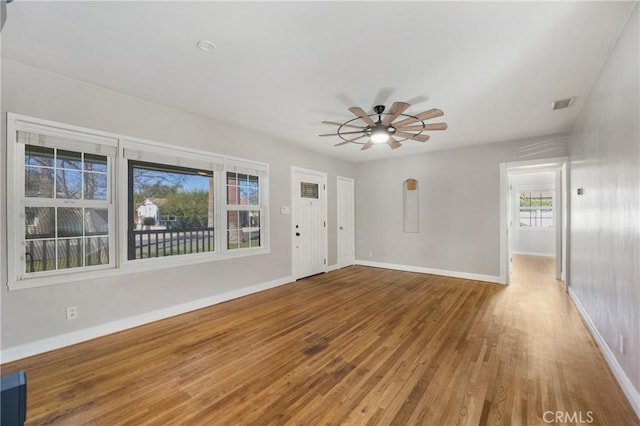 interior space with visible vents, ceiling fan, baseboards, and wood finished floors