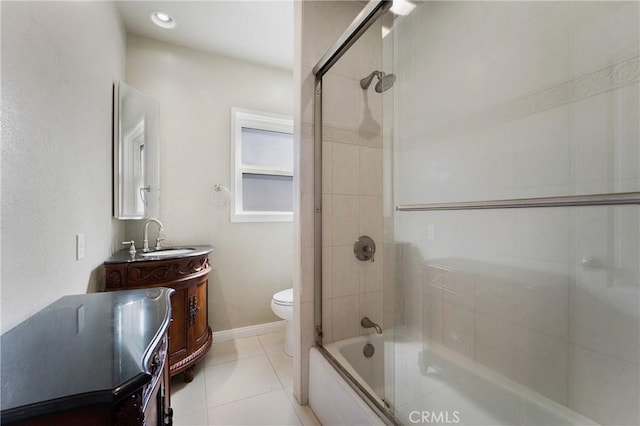 bathroom with toilet, combined bath / shower with glass door, vanity, baseboards, and tile patterned floors