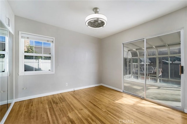 spare room with baseboards and wood finished floors