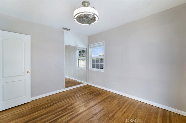 unfurnished bedroom featuring visible vents, baseboards, and wood finished floors