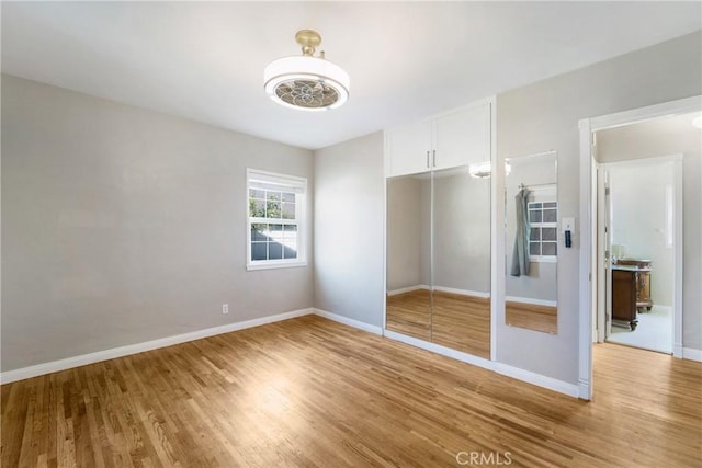 unfurnished bedroom with light wood-style floors, baseboards, and a closet