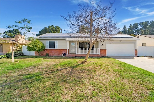 ranch-style home with brick siding, covered porch, roof mounted solar panels, fence, and a front lawn