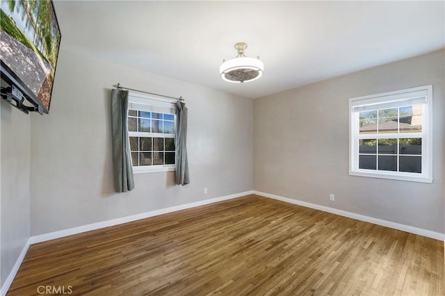 spare room with baseboards and wood finished floors