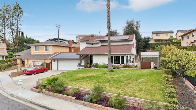 view of front of home with solar panels, fence, a garage, driveway, and a front lawn