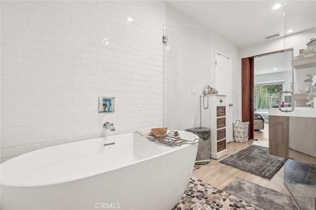 ensuite bathroom with ensuite bathroom, recessed lighting, wood finished floors, visible vents, and a freestanding bath