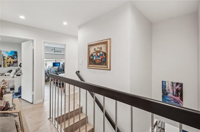 hall with light wood-type flooring, recessed lighting, and an upstairs landing