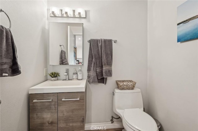 bathroom featuring baseboards, vanity, and toilet