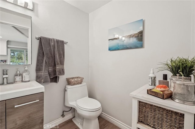 bathroom with toilet, baseboards, wood finished floors, and vanity