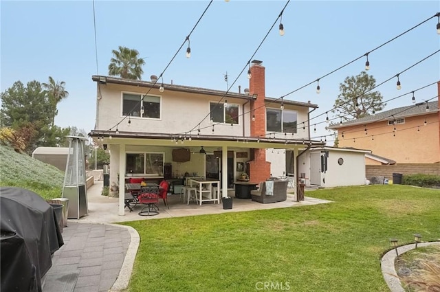 back of property with an outdoor hangout area, a patio, a lawn, and stucco siding