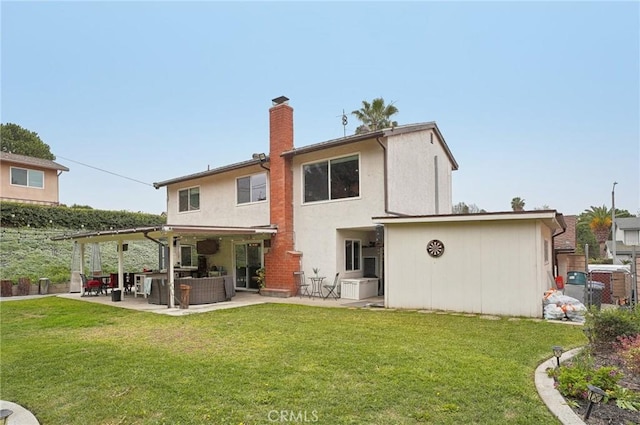 rear view of house featuring a yard, a patio, a chimney, and an outdoor living space