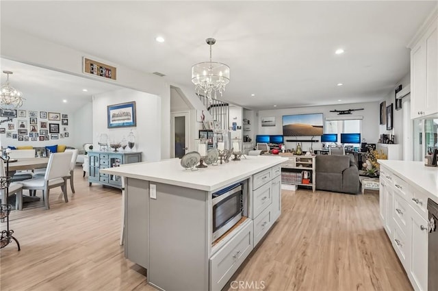 kitchen with a chandelier, light countertops, stainless steel microwave, and open floor plan