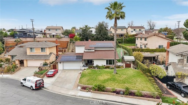 exterior space with driveway, a residential view, a front lawn, and solar panels