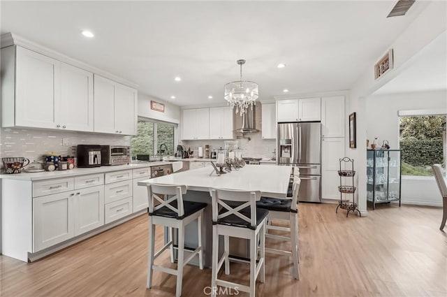 kitchen featuring a breakfast bar area, visible vents, white cabinets, light countertops, and stainless steel fridge