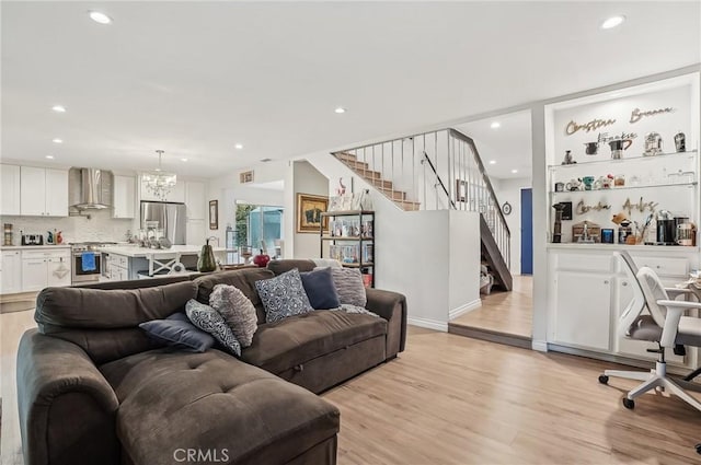 living area with a chandelier, recessed lighting, visible vents, stairs, and light wood finished floors