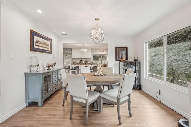 dining area with a healthy amount of sunlight, a notable chandelier, and light wood-style flooring