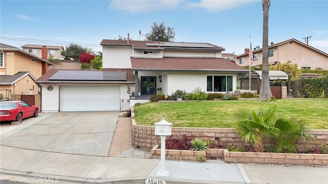 traditional home featuring a garage, solar panels, fence, concrete driveway, and a front lawn