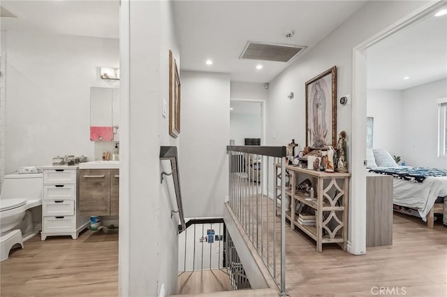 corridor with visible vents, recessed lighting, an upstairs landing, and light wood-style floors