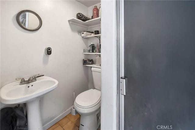 bathroom with baseboards, a sink, toilet, and tile patterned floors