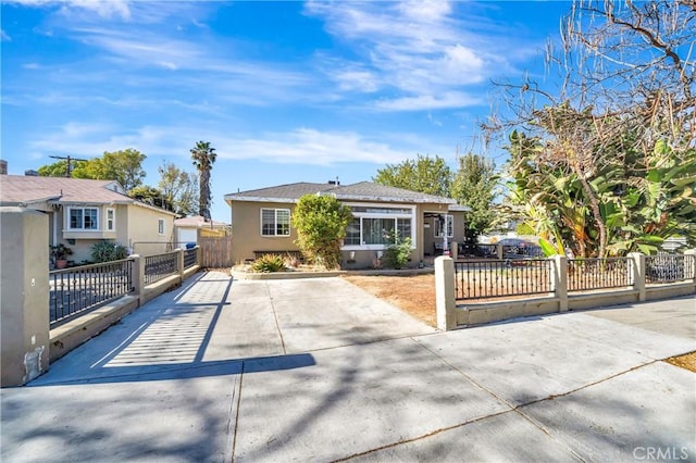 view of front of home featuring a fenced front yard, a gate, driveway, and stucco siding