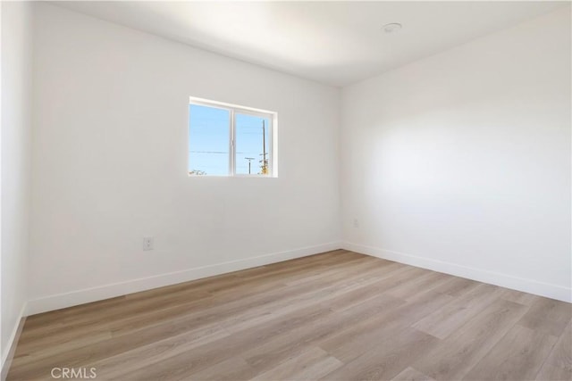 empty room with baseboards and light wood-type flooring