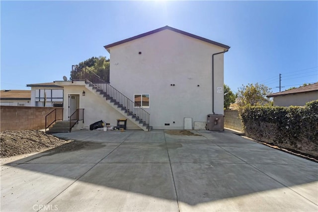 back of property featuring stairs, a patio area, fence, and stucco siding