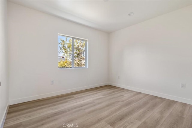 spare room featuring baseboards and light wood finished floors