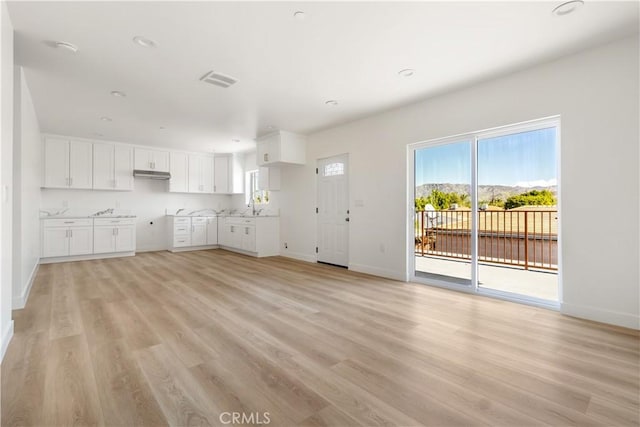 unfurnished living room featuring baseboards, light wood-style floors, and a sink