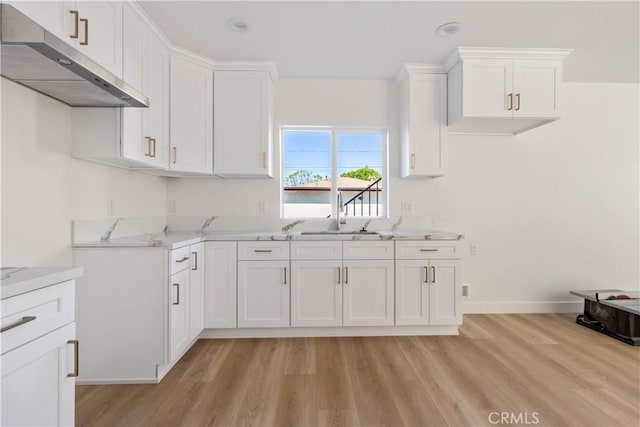 kitchen with white cabinetry, light wood-style floors, under cabinet range hood, and a sink