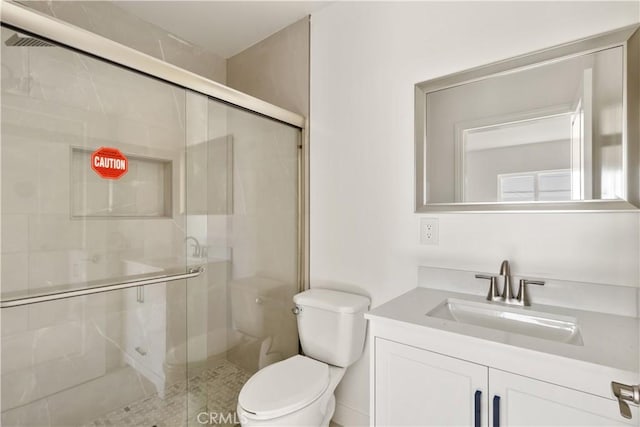 bathroom with a shower stall, toilet, and vanity