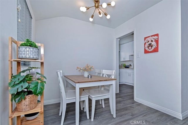 dining space featuring vaulted ceiling, baseboards, an inviting chandelier, and wood finished floors