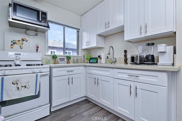 kitchen featuring stainless steel microwave, white cabinets, light countertops, and white gas range