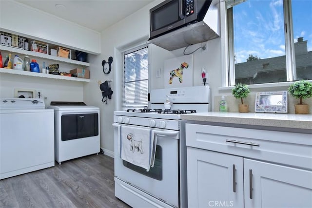 kitchen featuring wood finished floors, white gas range oven, white cabinetry, stainless steel microwave, and washing machine and dryer