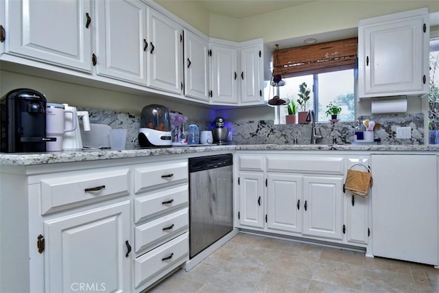 kitchen featuring light stone counters, a sink, white cabinets, dishwasher, and stainless steel dishwasher