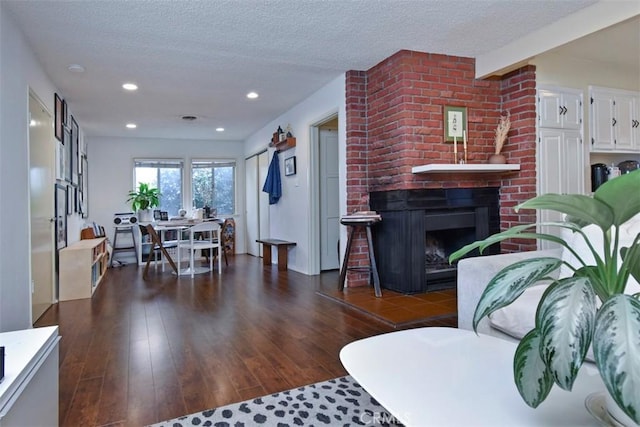 living room with recessed lighting, a fireplace, wood-type flooring, and a textured ceiling